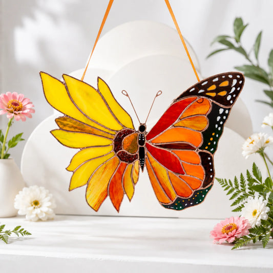 A gorgeous stained glass sunflower-monarch butterfly hanging against a clean backdrop with flowers, serving as an enchanting gift choice.