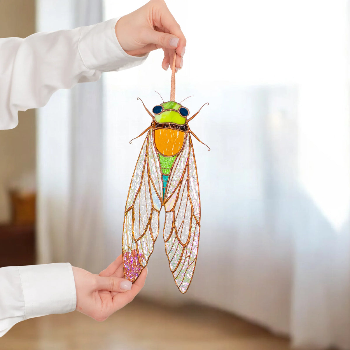 A person holding a handcrafted stained glass cicada, showcasing its vibrant colors and intricate details as a thoughtful gift.