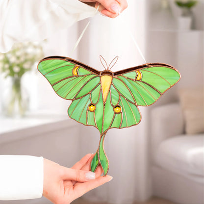 A person holding up a handcrafted green stained glass luna moth, highlighting its detailed design and beauty as a special present.