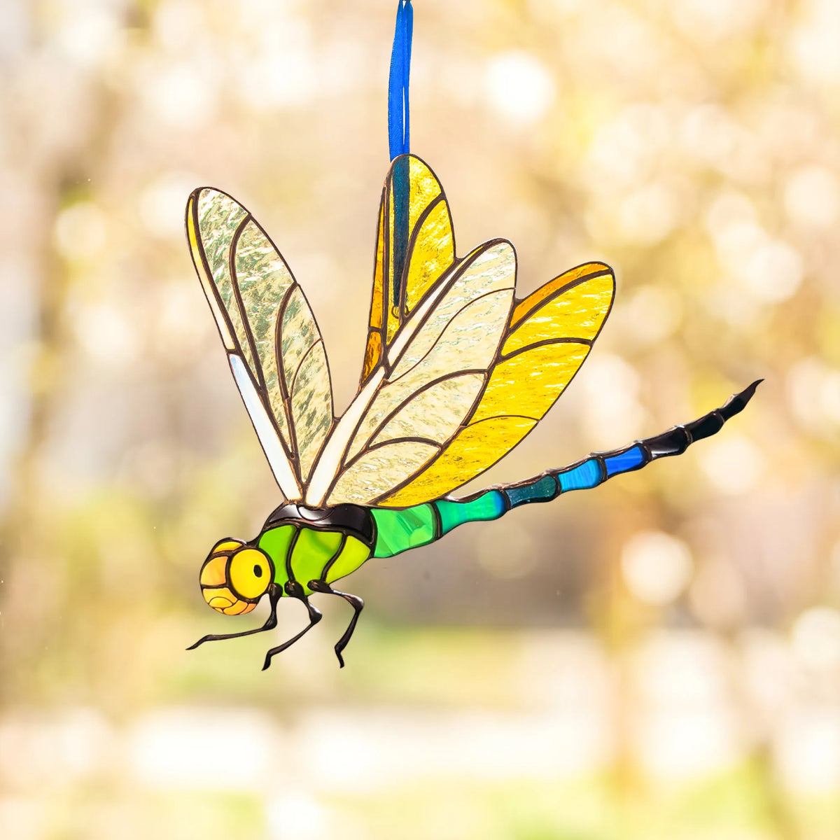 A vibrant stained glass dragonfly hanging outdoors, catching the sunlight to make a wonderful gift for any occasion.