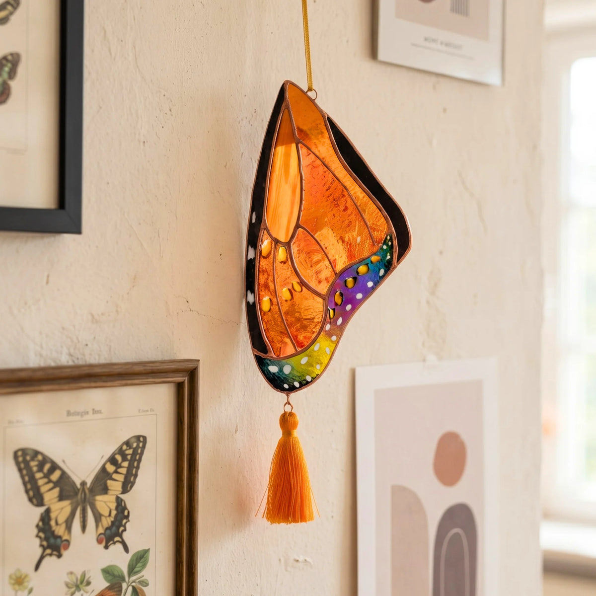 A vibrant stained glass butterfly wing hanging on a textured wall, serving as a charming and unique home decor piece.