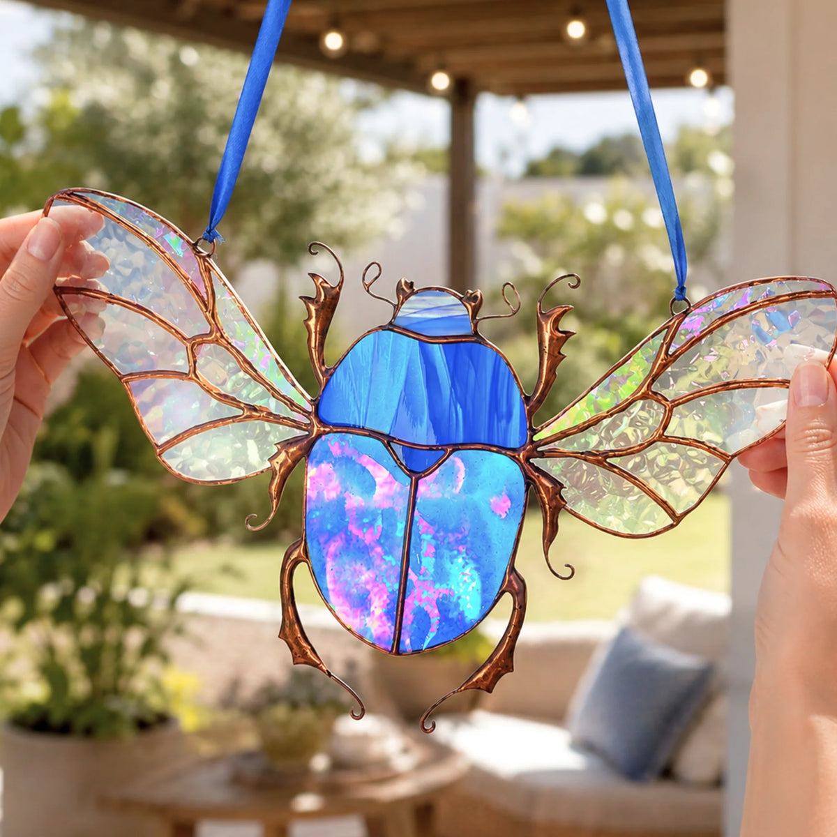 Hands holding stained glass scarab beetle suncatcher