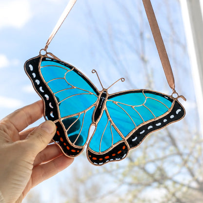Hand holding stained glass morpho buterfly suncatcher window hanging