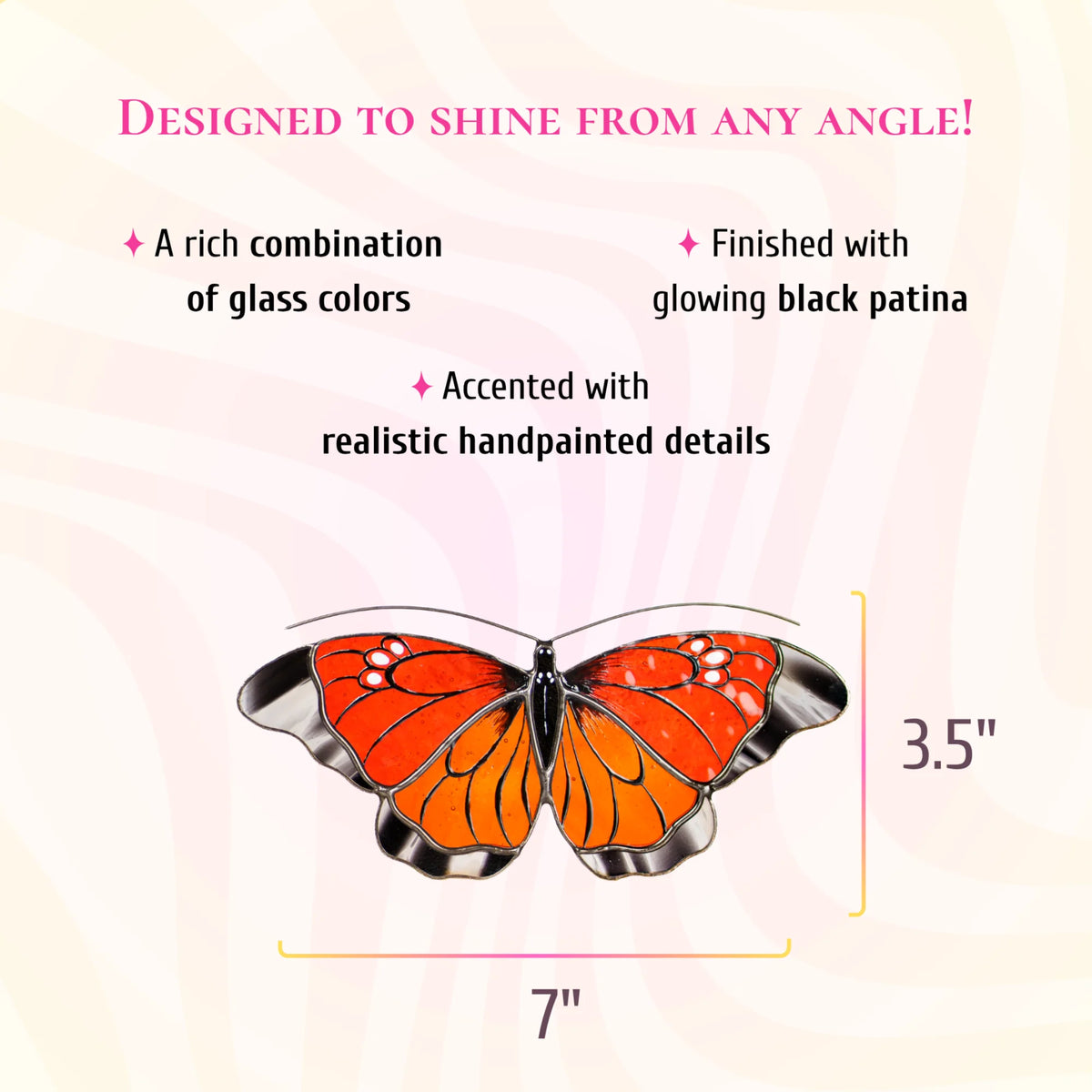 Orange and red stained glass butterfly suncatcher with black and white wing tips, 7 inches wide and 3.5 inches tall. Text: designed to shine from any angle. A rich combination of glass colors, finished with glowing black patina and accented with realistic hand-painted details.
