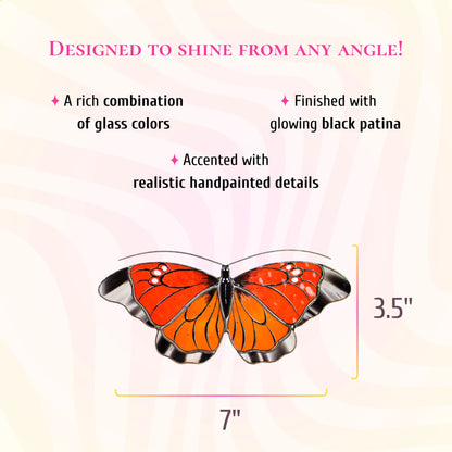 Orange and red stained glass butterfly suncatcher with black and white wing tips, 7 inches wide and 3.5 inches tall. Text: designed to shine from any angle. A rich combination of glass colors, finished with glowing black patina and accented with realistic hand-painted details.
