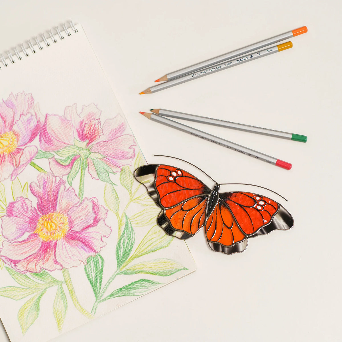 Orange stained glass butterfly suncatcher with clear wing edges and white spots, on a peony sketch