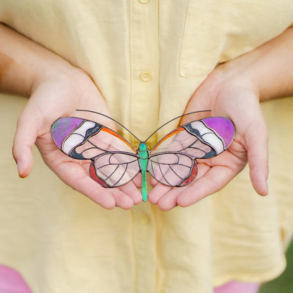 Glasswing butterfly stained glass suncatcher with purple wingtips held in open palms