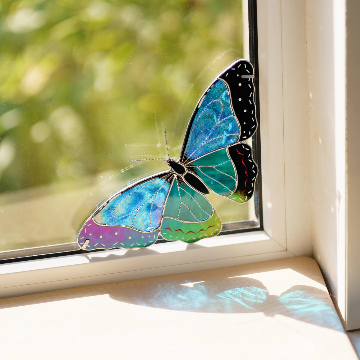 Handmade stained glass morpho butterfly window corner suncatcher casting blue light onto the sill