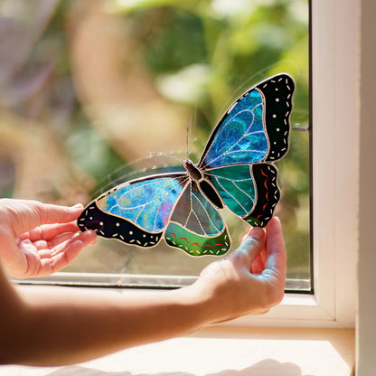 Hands placing the blue and teal morpho into a window corner, a metal clip on the frame
