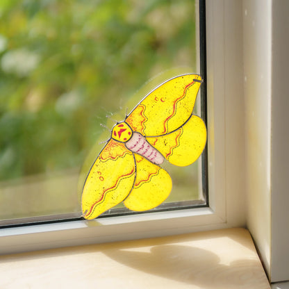 Handmade stained glass imperial moth window corner suncatcher clipped into a sunny window corner