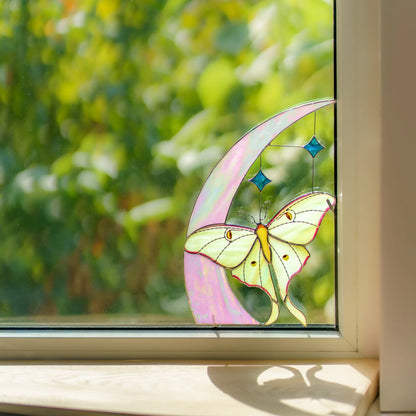 Celestial window corner with an iridescent pink moon and blue glass stars in a sunlit window