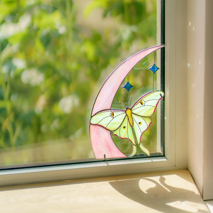 Luna moth and moon glass art fitted into a window corner, its shadow falling across the sill