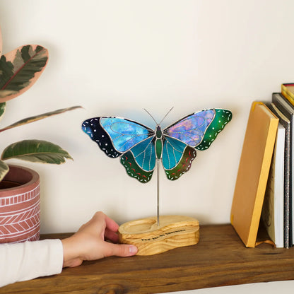 Hand placing the blue morpho butterfly suncatcher's wooden base on a bookshelf