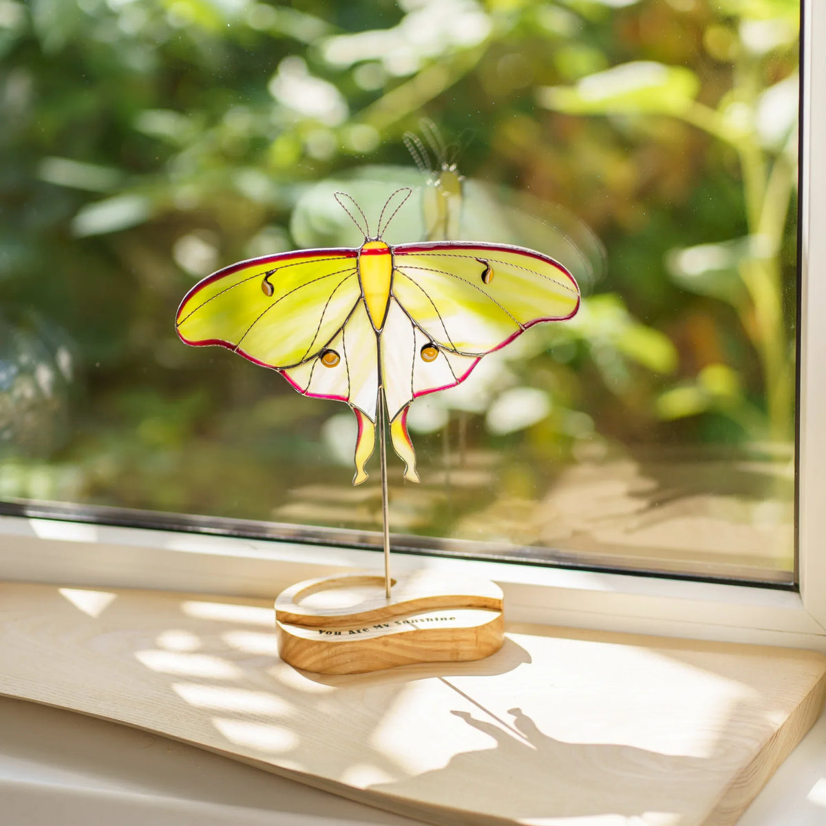 Close-up of the luna moth suncatcher's stained glass wings catching window light