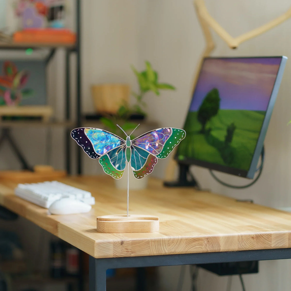 Blue morpho butterfly suncatcher on a wooden desk stand next to a keyboard and monitor