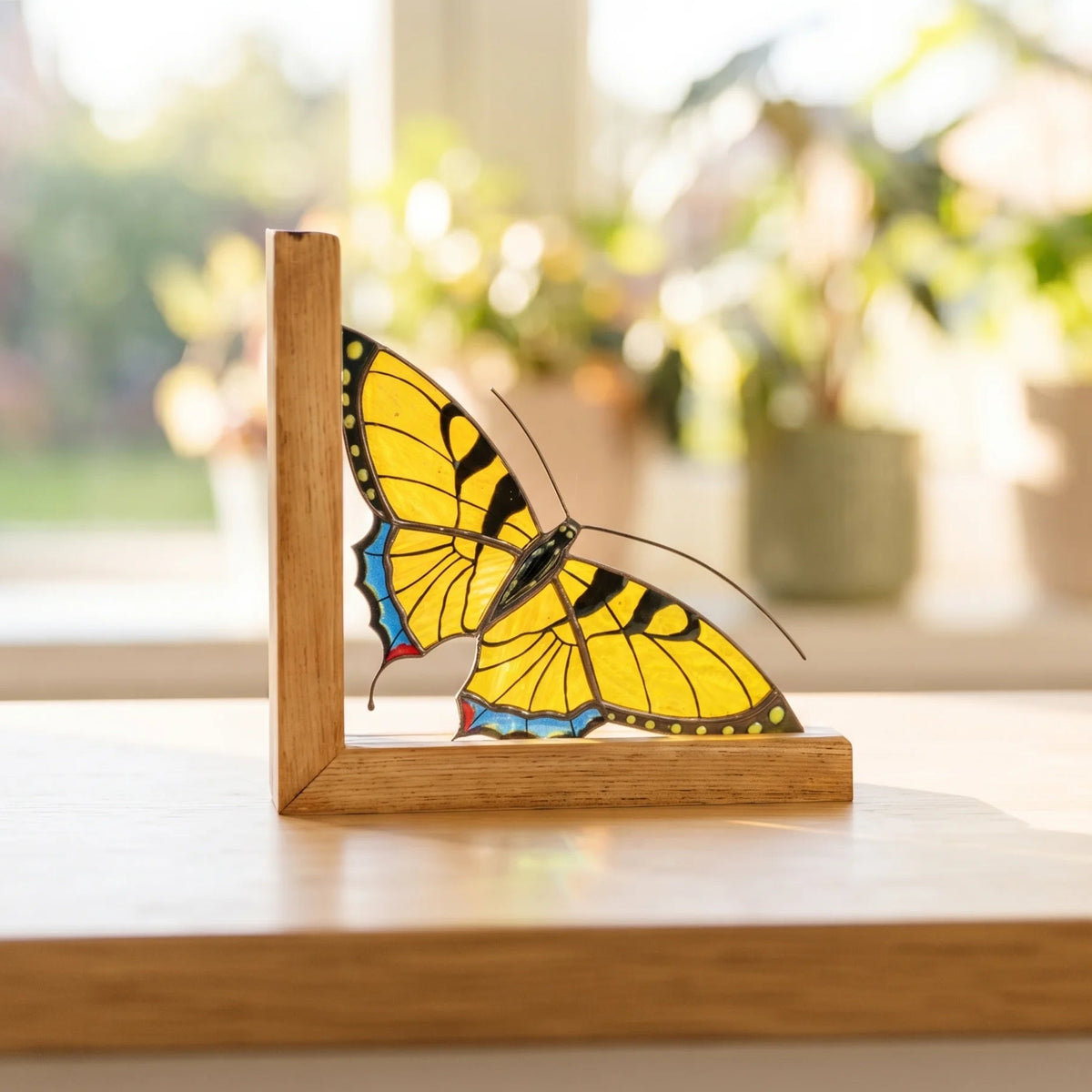 This elegant yellow stained glass butterfly bookend sits gracefully on a sunlit windowsill, making a lovely decorative gift choice.