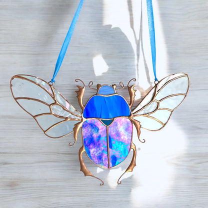 Stained glass scarab beetle suncatcher, hanging near a sunny wall