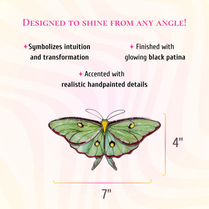 Pale green luna moth stained glass suncatcher with burgundy edges, yellow eyespots and short tails, 7 inches wide and 4 inches tall. Text: designed to shine from any angle. A rich combination of glass textures, finished with glowing black patina and accented with realistic hand-painted details.
