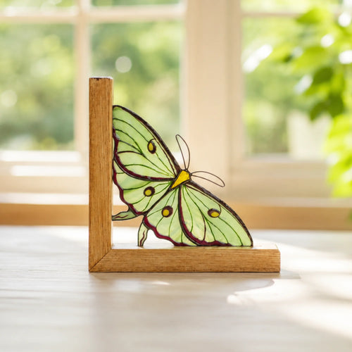 Stained glass actias luna moth bookend table decor staying on a windowsill 