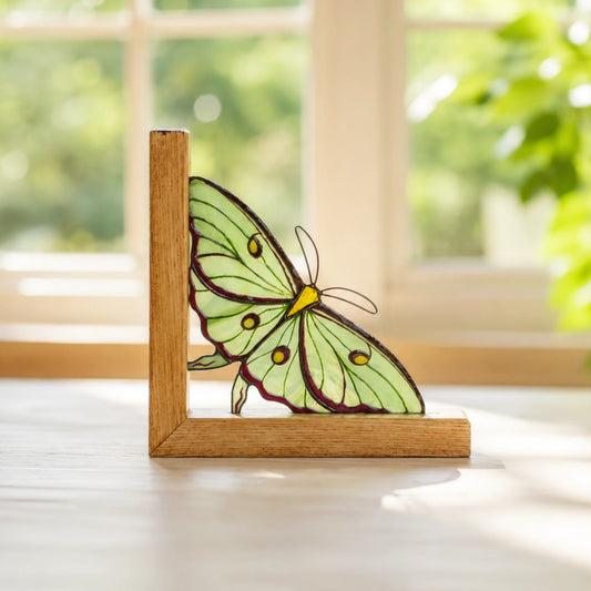 Stained glass actias luna moth bookend table decor staying on a windowsill 