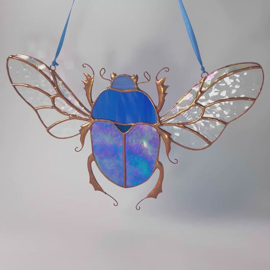 A lovely video highlighting a handcrafted stained glass blue scarab, capturing how it beautifully enhances any shelf or space with its artistic design.